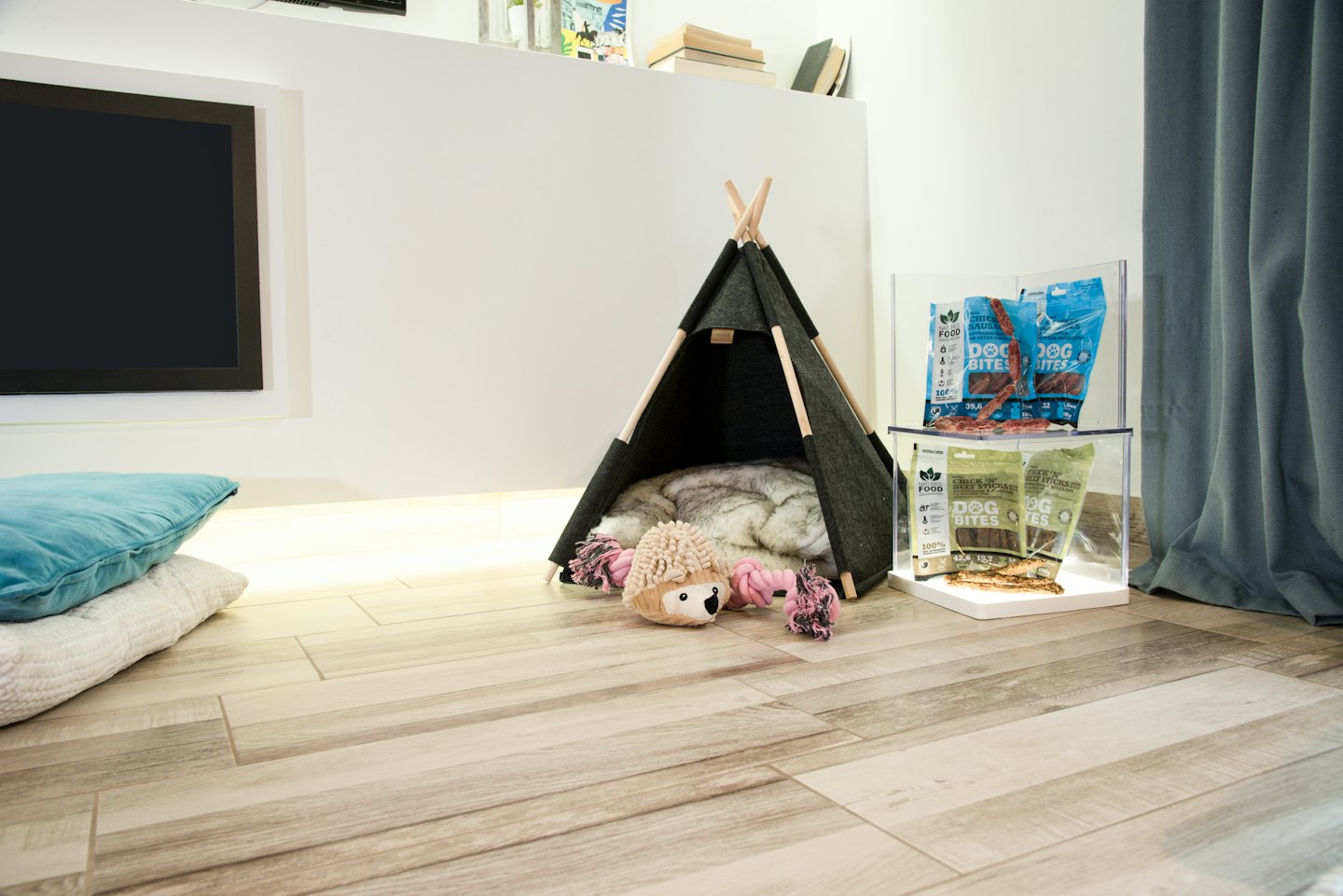 Ein graues Haustier-Tipi mit Spielzeug und Leckerlis auf dem Boden.